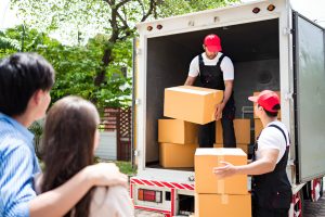 Asian and Caucasian workers in uniform unloading cardboard boxes from the truck.