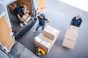 Uniformed Team of Delivery Drivers Loading Packages on Van