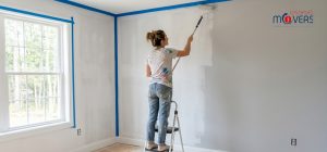 A person painting a bedroom wall in a new house using a roller and blue tape A person painting a bedroom wall in a new house using a roller and blue tape